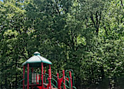 Thumbnail 11 of 17 - A red playground in front of  trees.