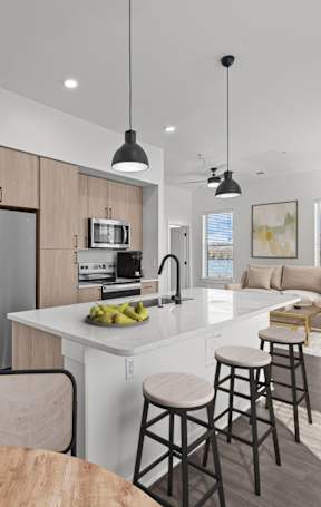 A modern kitchen with a refrigerator, sink, and bar stools.