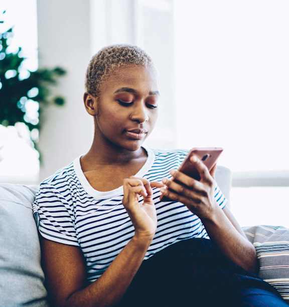 A person is sitting on a couch looking at a phone.