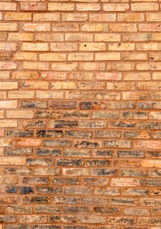 A brick wall with a white and blue striped cloth hanging on the left side.