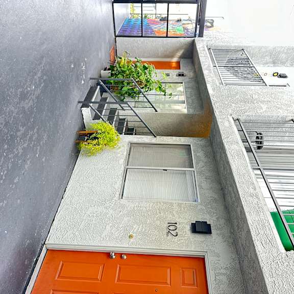 a view of a courtyard with stairs and an orange door at The Marq Apartments LLC, Los Angeles