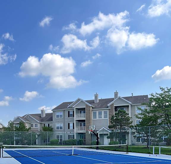 a view of a tall building with a blue facade and a blue sky with clouds at Landings at Amhurst Lake Apartments, Waukegan