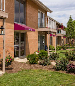 A row of apartment buildings with green bushes in front.