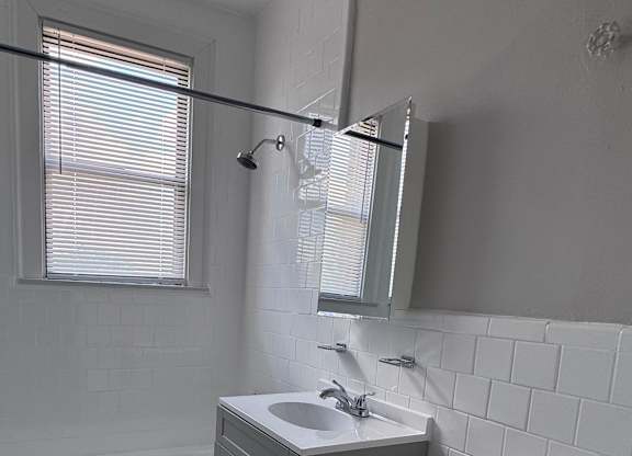 A bathroom with a toilet, sink, and a window.