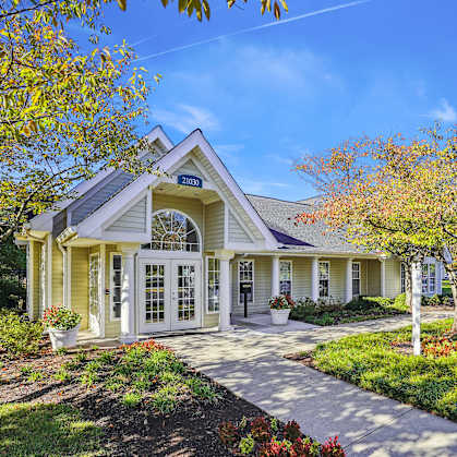 A house with a front yard and a tree with red leaves.