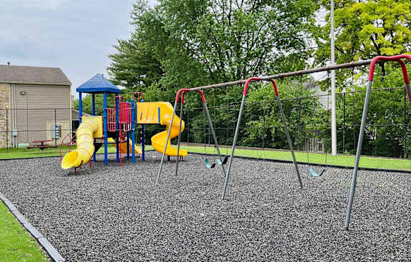 A playground with a yellow slide and a blue canopy.