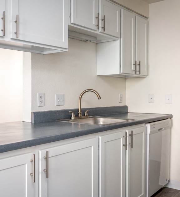 an empty kitchen with white cabinets and a sink