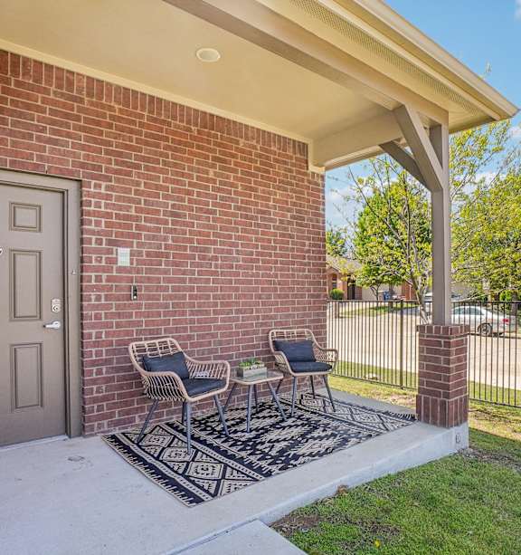 A house with a grey door and a small porch with two chairs.