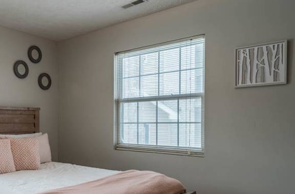 A bedroom with a bed, nightstand, and window.