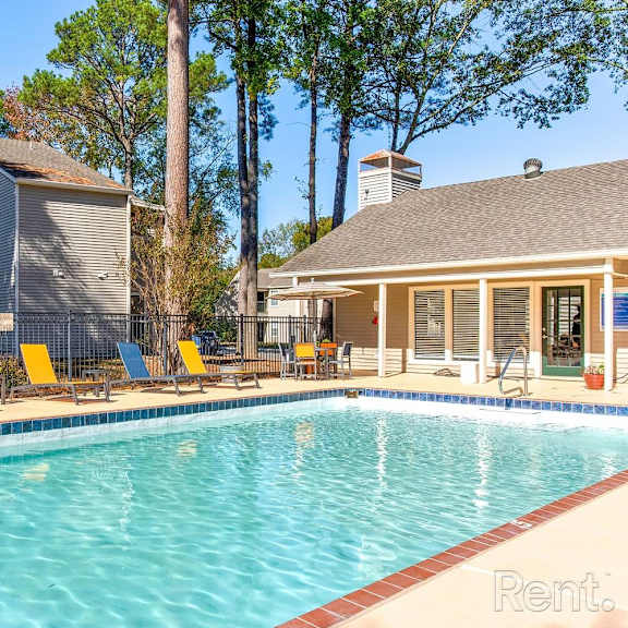 A pool with chairs and a house in the background.