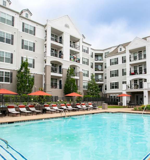 A large swimming pool surrounded by lounge chairs and umbrellas.