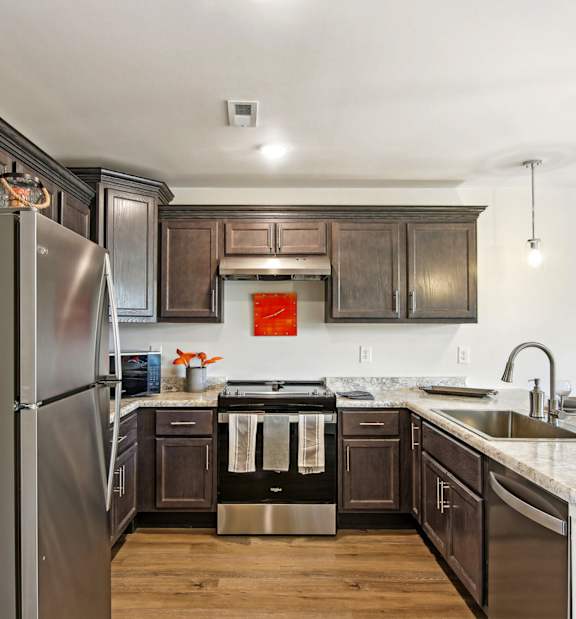 A modern kitchen with dark wood cabinets and stainless steel appliances.