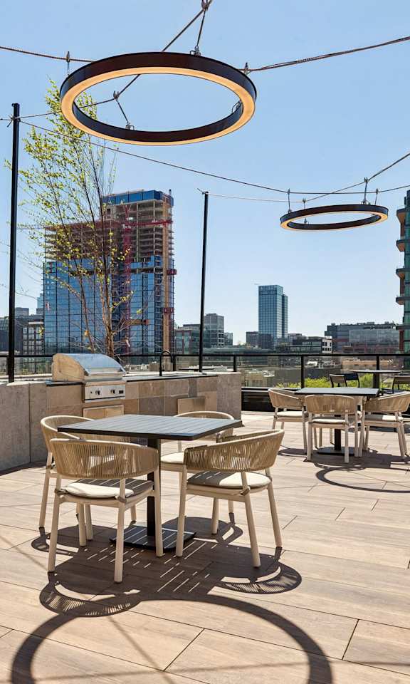 A patio with tables and chairs overlooking a body of water.