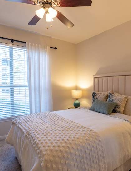 a bedroom with a large bed and a ceiling fan at The Park at Monterey Oaks, Austin, TX