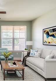 A living room with a couch, chair, and potted plant.