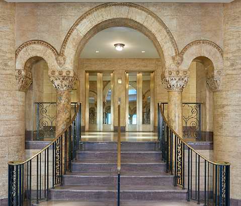 a long hallway with columns and stairs and doors