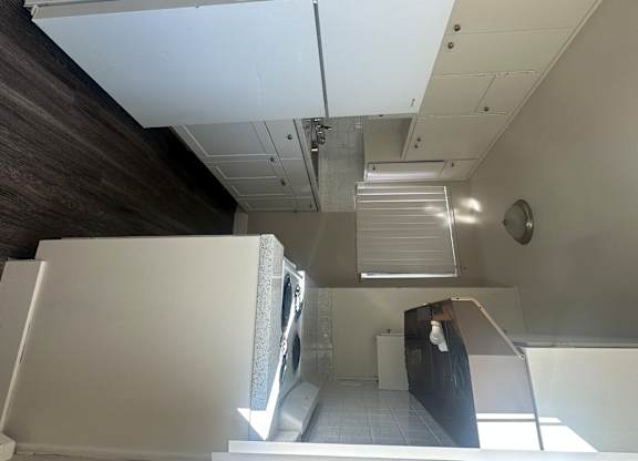 A white refrigerator is in a kitchen with a white wall and a white ceiling.