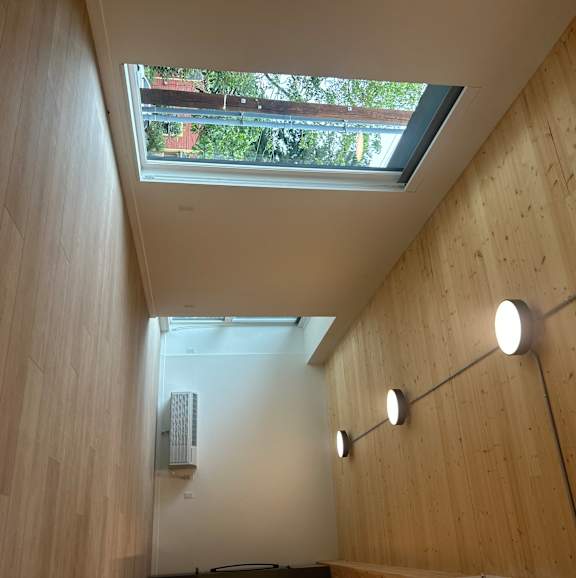 A long hallway with lights on the wall and a skylight.