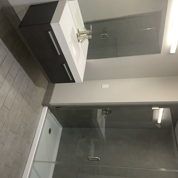 Large spacious bathrooms feature ample lighting, floating vanities, and large showers with full glass doors.