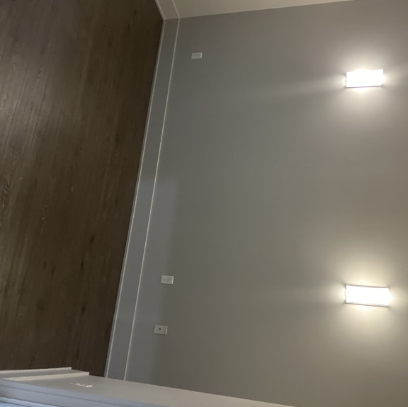A sizable bedroom with modern sconces large enough to accomodate a King size bed with end tables.