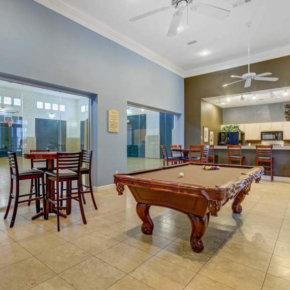 A pool table is in the middle of a room with a glass wall.