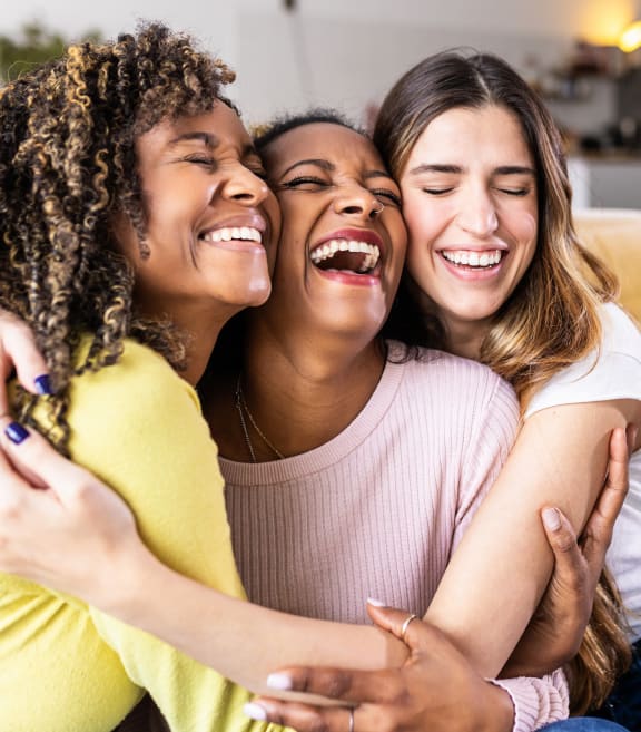 a group of women sitting on a couch with their arms around each other