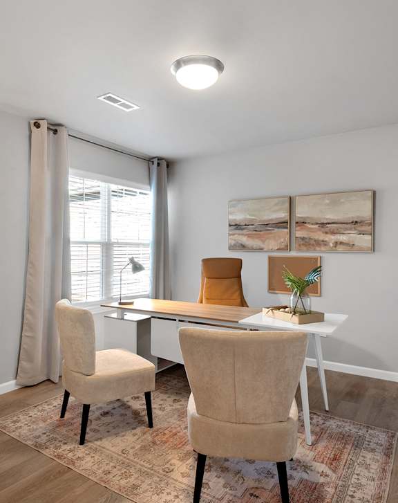 A room with a desk, chairs, and pictures on the wall.