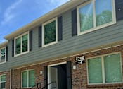 Thumbnail 2 of 17 - Apartment building with green siding and a blue sky above.
