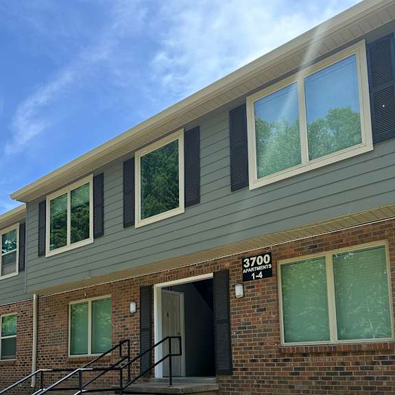 Apartment building with green siding and a blue sky above.