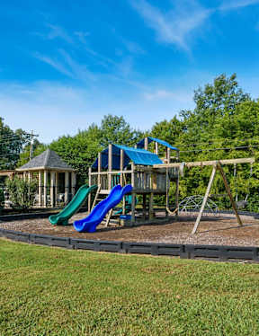 A playground with a blue slide and a brown sandbox.
