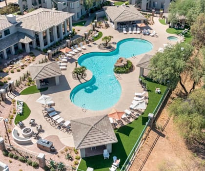 A large swimming pool surrounded by a grassy area and a few trees.