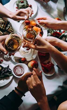 A group of people toasting with drinks at a dinner table.
