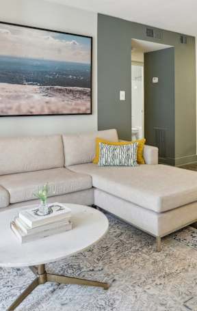 A living room with a white couch and a large landscape painting on the wall.