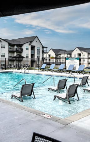 a swimming pool with chaise lounge chairs at Tiburon Ridge, Omaha, NE