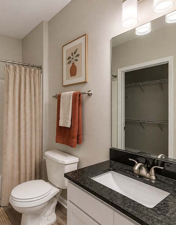 A bathroom with a white toilet, a white sink, a white bathtub, and a shower curtain.
