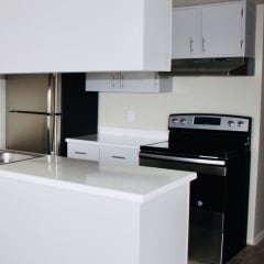a small kitchen with white cabinets and black appliances