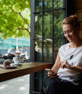 Woman Having Coffee While on Phone Smiling
