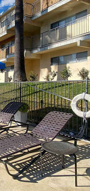 A pool area with chairs and umbrellas in front of a building.