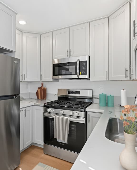 A kitchen with a stainless steel refrigerator, microwave, oven, and sink.