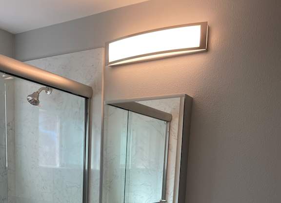 A bathroom with a glass shower stall and a white cabinet.
