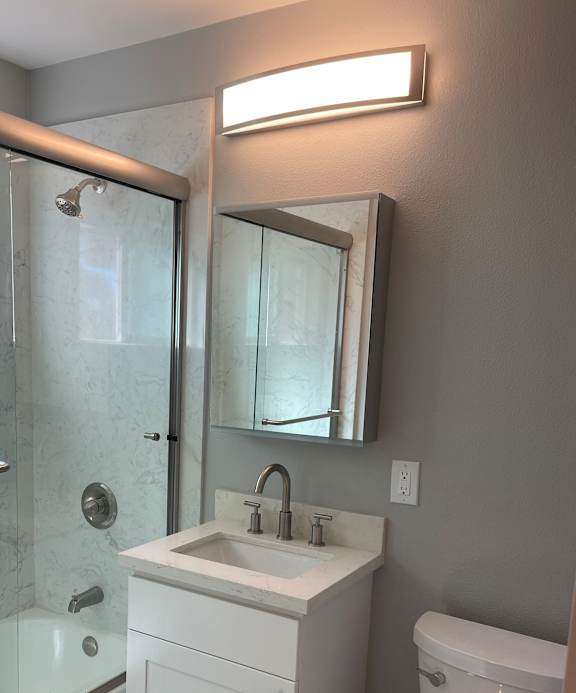 A bathroom with a glass shower stall and a white cabinet.