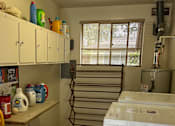 Thumbnail 21 of 38 - A kitchen with white cabinets and a white counter top with many items on it.