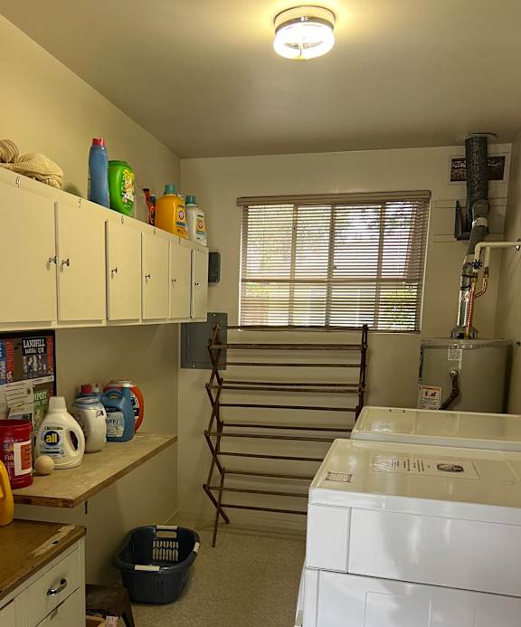 A kitchen with white cabinets and a white counter top with many items on it.
