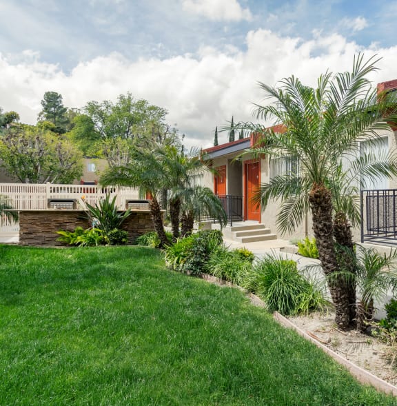 a house with orange doors and a lawn and palm trees