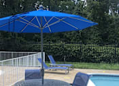 Thumbnail 29 of 29 - A blue umbrella is next to a pool with a chair underneath it. at New Carrollton Woods, Riverdale, MD