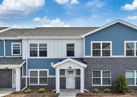 A blue and white townhouse with a front yard and a driveway.at Hawthorne Pointe, Bondurant, 50035