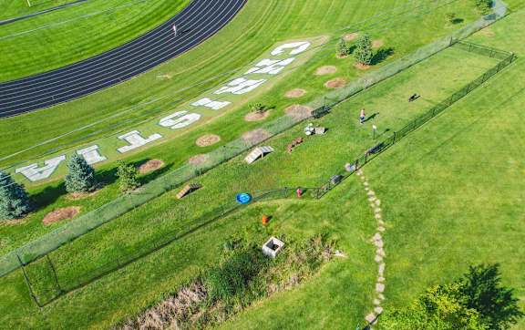 grassy area with fenced dog park and running track in background