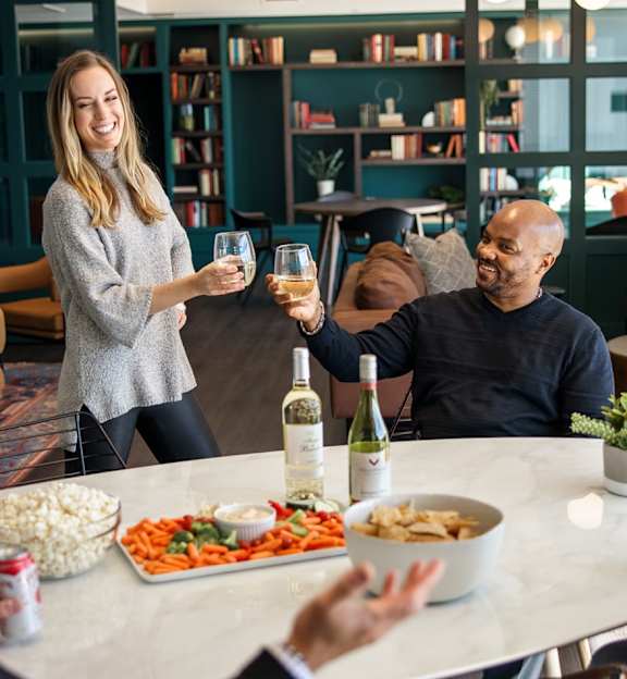 A group of people are gathered around a table with food and drinks. at Trio Newton Apartments, Newton, Massachusetts