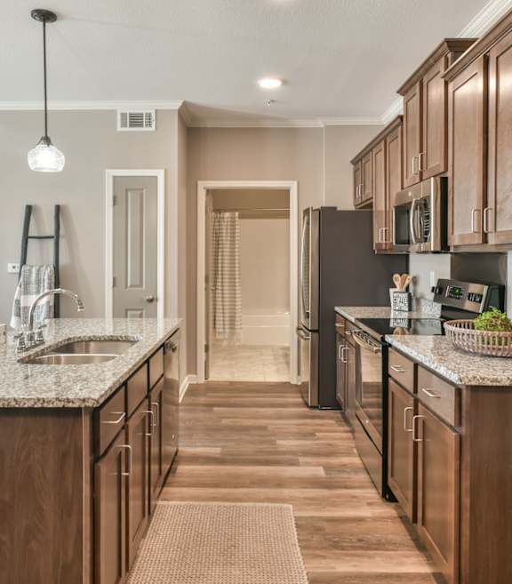 A kitchen with a black refrigerator, white cabinets, and a granite countertop.