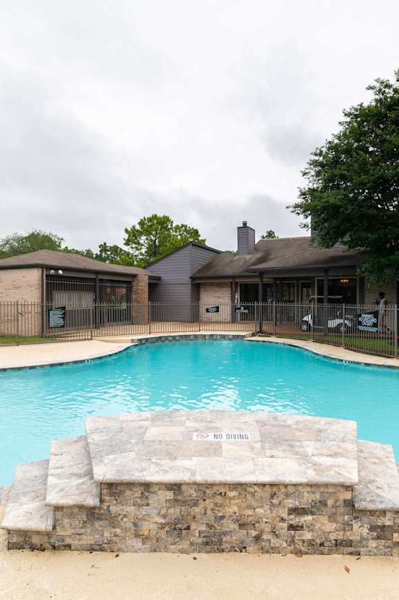 a swimming pool with orange chairs and a building in the background